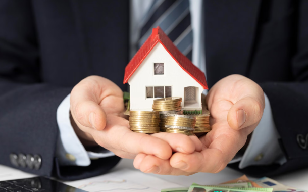 A photo of a man holding a house and coins